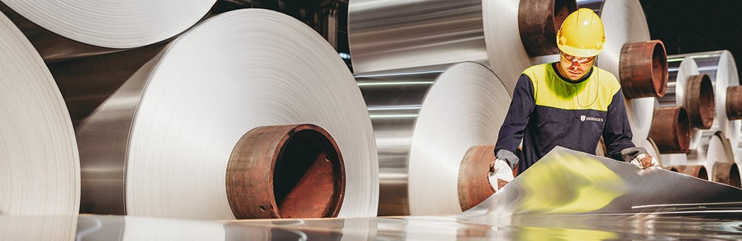 Employee examining flat rolled aluminium.